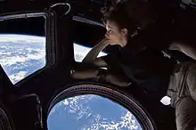 Woman looking at Earth through a glass cupola